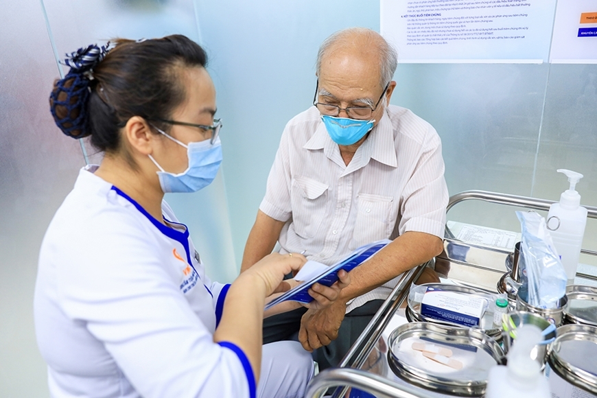 Nhân viên y tế tư vấn cho người dân trước khi tiêm vắc xin (Ảnh TL)