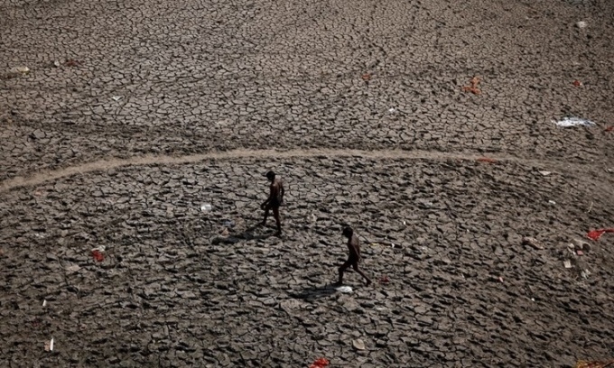 Hai người đàn ông đi bộ qua một lòng sông khô cạn ở New Delhi, Ấn Độ, ngày 30/4. Ảnh: Reuters.