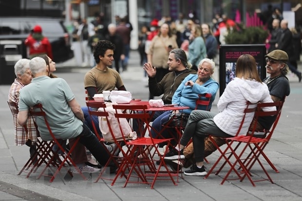 Người dân thư giãn tại một quán ăn ngoài trời ở quảng trường Thời đại, New York (Mỹ) khi các quy định phòng dịch COVID-19 được nới lỏng (Ảnh: THX/TTXVN)