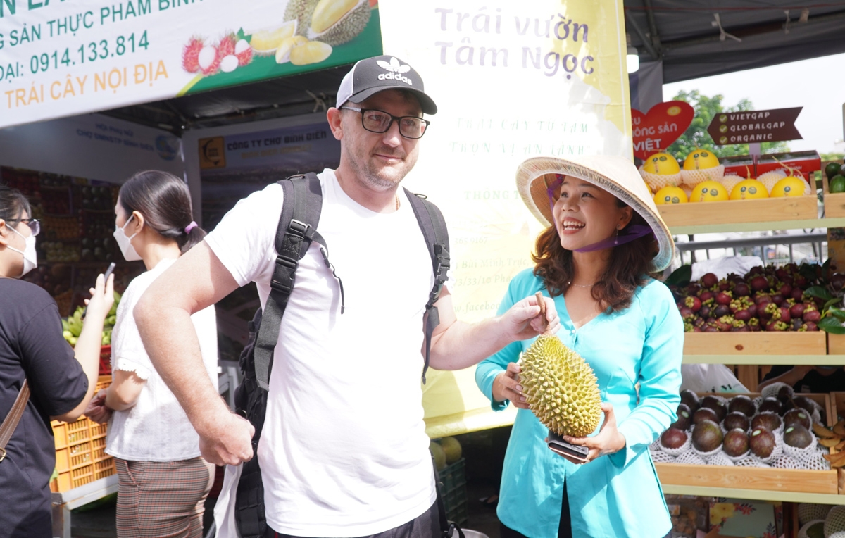Một du khách nước ngoài đang tham quan và nghe giới thiệu về trái cây Việt Nam