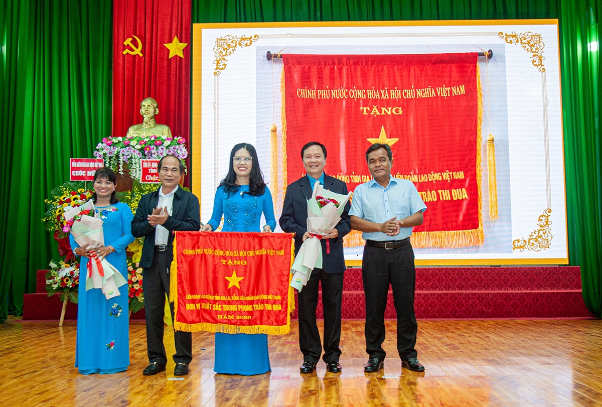 Bí thư Tỉnh ủy Gia Lai Hồ Văn Niên (bìa phải) và Chủ tịch UBND tỉnh Võ Ngọc Thành (thứ hai từ trái qua) thừa ủy quyền của Thủ tướng Chính phủ trao Cờ thi đua xuất sắc của Chính phủ cho LĐLĐ tỉnh tại Lễ tuyên dương