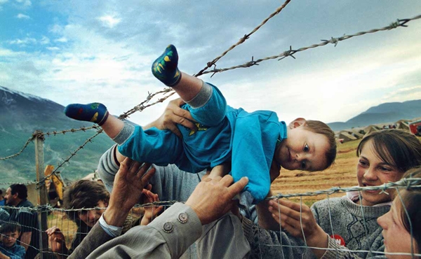 Bức ảnh đoạt giải Pulitzer về một đứa bé được chuyển qua hàng rào dây thép gai để thăm gia đình ở Albania do phóng viên ảnh Carol Guzy thực hiện