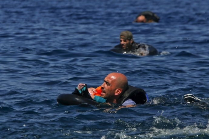 Người tị nạn Syria ôm đứa con nhỏ bơi vào bờ sau khi thuyền cao su của họ bị xì hơi cách đảo Lesbos của Hy Lạp khoảng 100m, ngày 13/9/2015. (Bức ảnh nằm trong chùm ảnh về người tị nạn đoạt giải Pulitzer 2016)