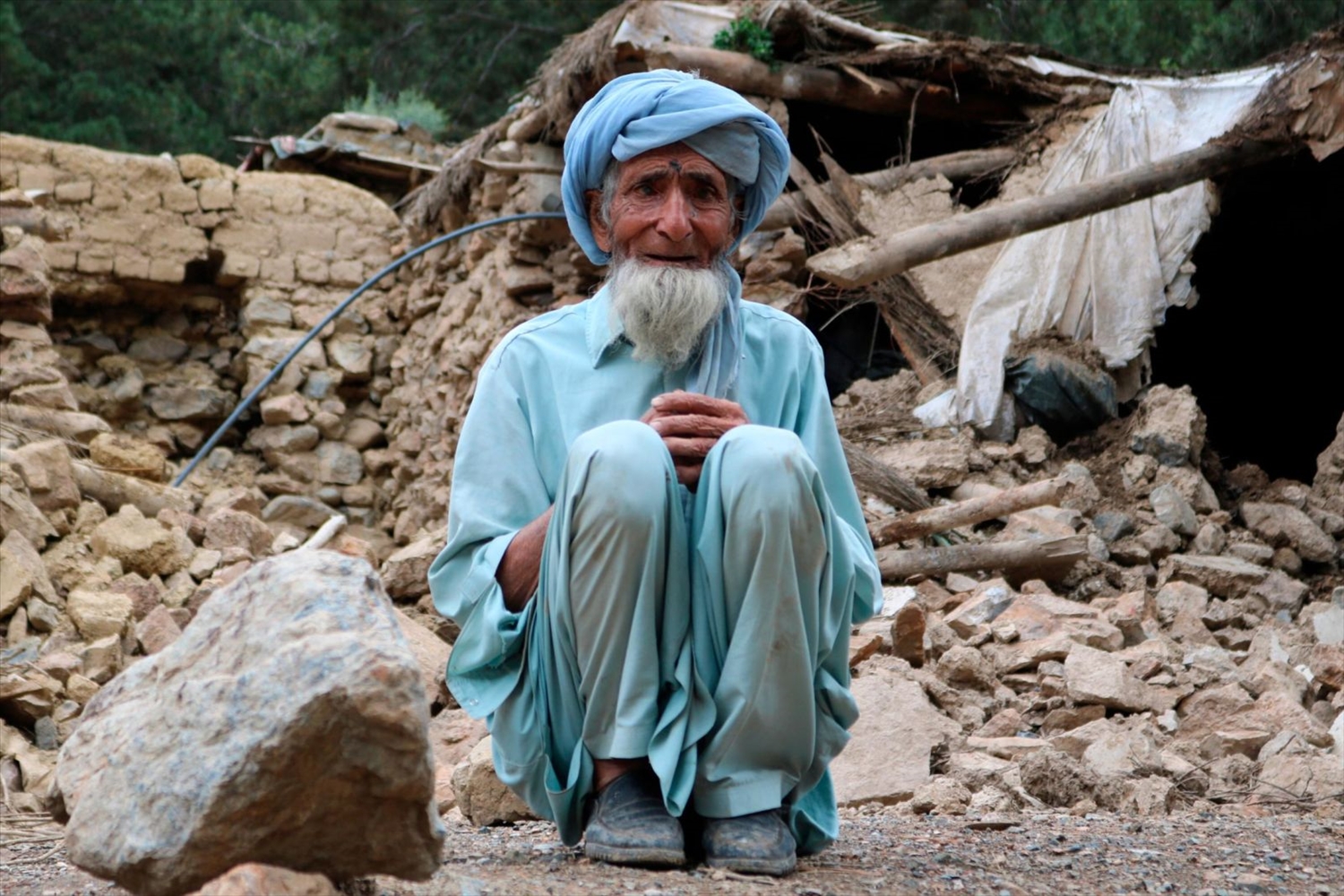 Một cụ già ngồi gần ngôi nhà của mình đã bị phá hủy trong trận động đất.