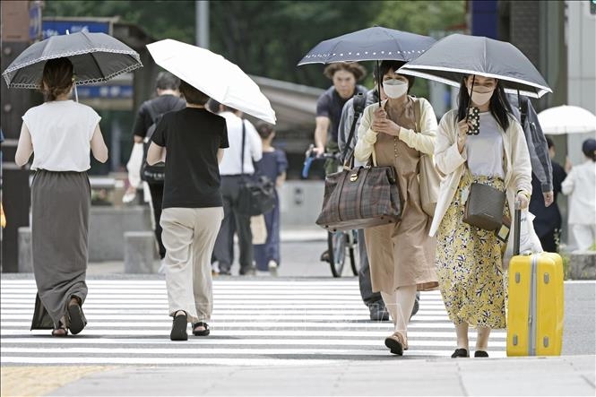 Người dân che ô tránh nắng khi di chuyển trên đường phố tại Nagoya, Nhật Bản, ngày 27/6/2022. Ảnh: Kyodo/ TTXVN