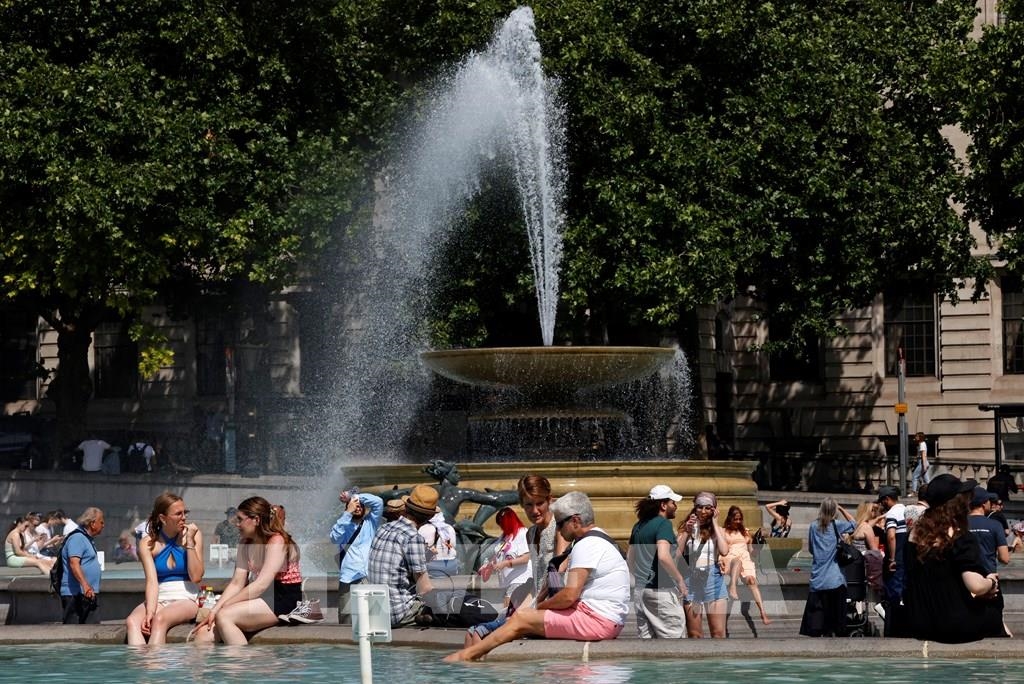 Người dân tránh nóng bên đài phun nước tại Quảng trường Trafalgar ở thủ đô London (Anh) Ảnh: AFP/ TTXVN