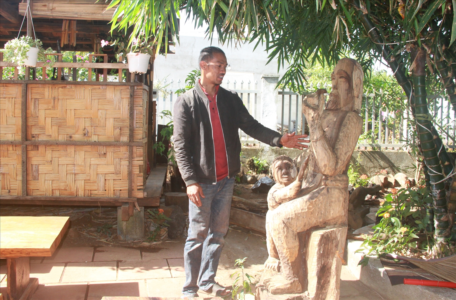 Bức tượng già làng hút thuốc và em bé của nghệ nhân Y Ser đang được trưng bày tại khuôn viên Homestay Hnoh Ea Kao