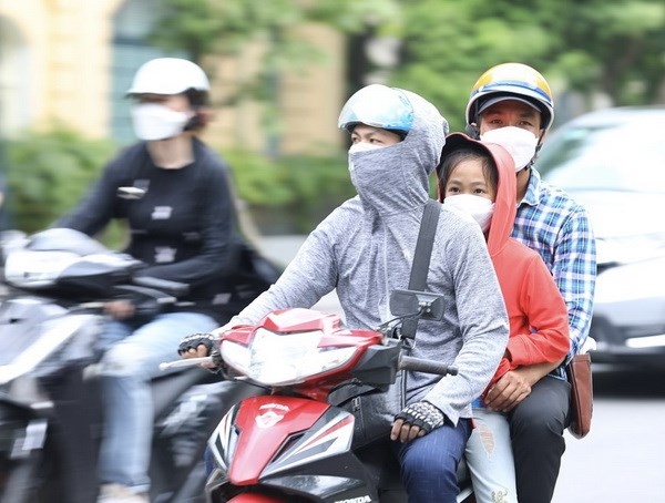 Người dân mặc đồ tránh nắng, nóng khi phải di chuyển trên đường. (Ảnh: Hoàng Hiếu/TTXVN)