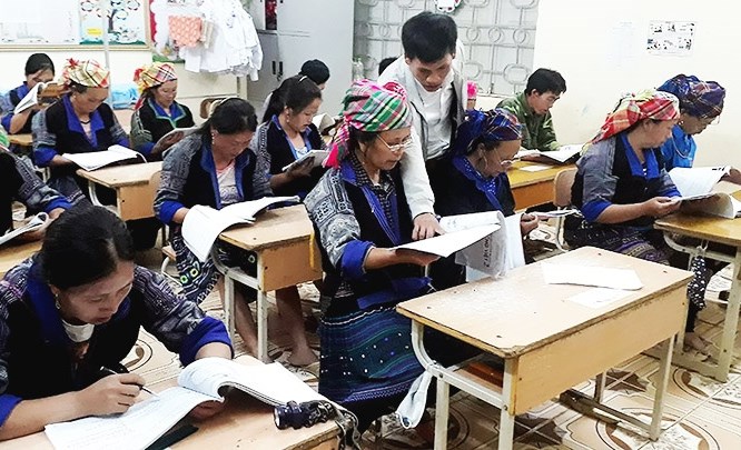 Thầy giáo hướng dẫn học viên đọc chữ tại lớp xóa mù chữ ở Tà Mung (Than Uyên, Lai Châu).