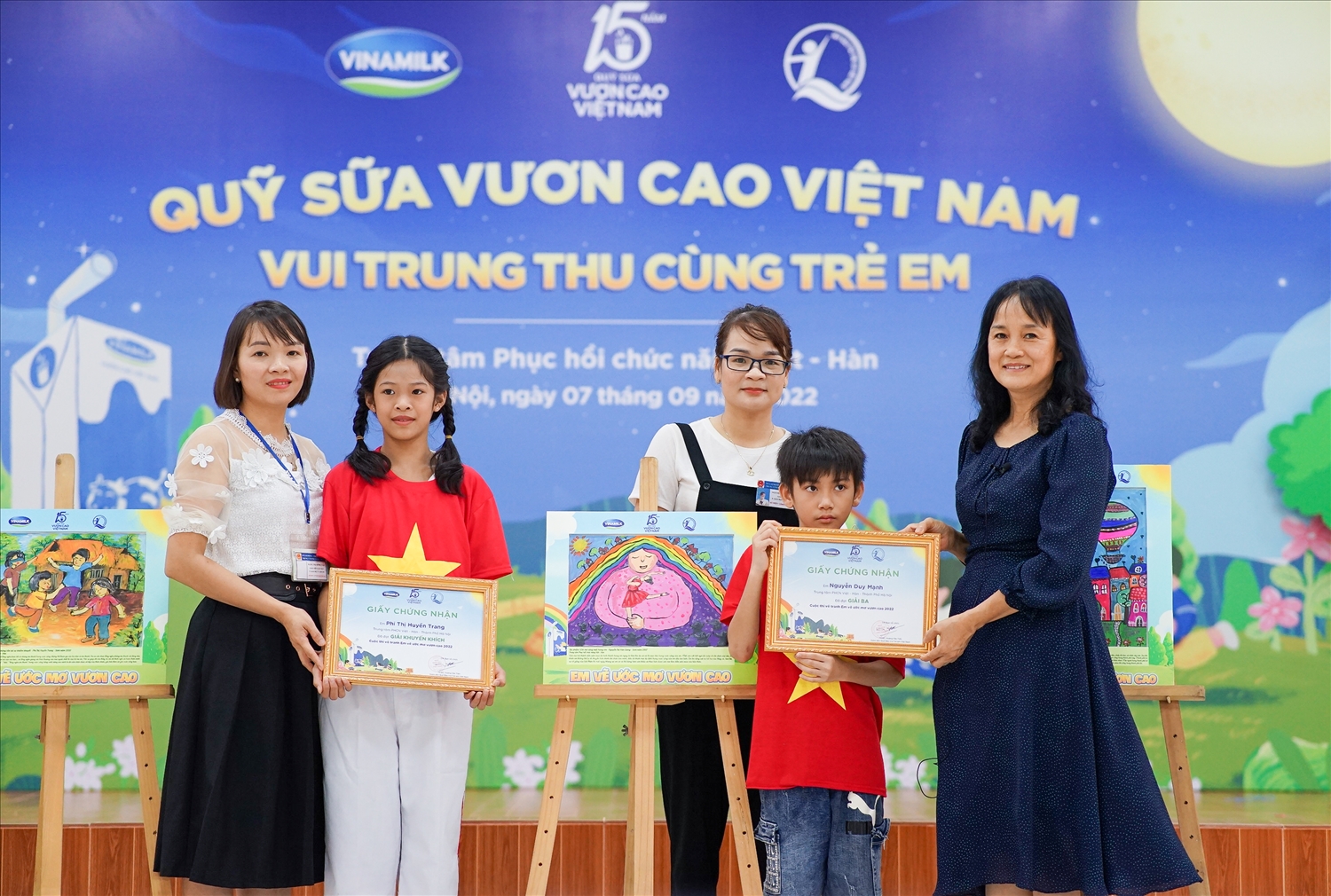 Em Phí Thị Huyền Trang (giải khuyến khích) và Nguyễn Duy Mạnh (giải ba) nhận quà từ đại diện công ty Vinamilk
