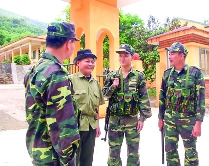 Cán bộ, chiến sĩ Đồn Biên phòng Trung Lý trao đổi với già làng Lương Văn Qúy về việc vận động quần chúng tham gia bảo vệ đường biên cột mốc