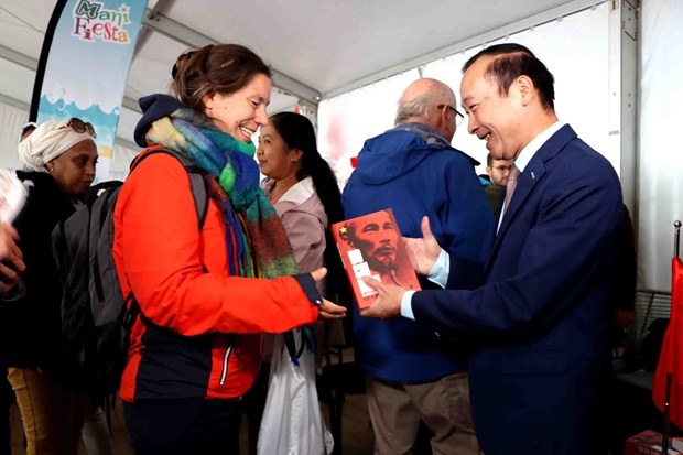 Ông Nguyễn Văn Thảo - Đại sứ Việt Nam tại Vương quốc Bỉ tặng sách về Chủ tịch Hồ Chí Minh cho độc giả nước ngoài tại lễ hội Manifesta. (Ảnh: Hương Giang/Vietnam+)