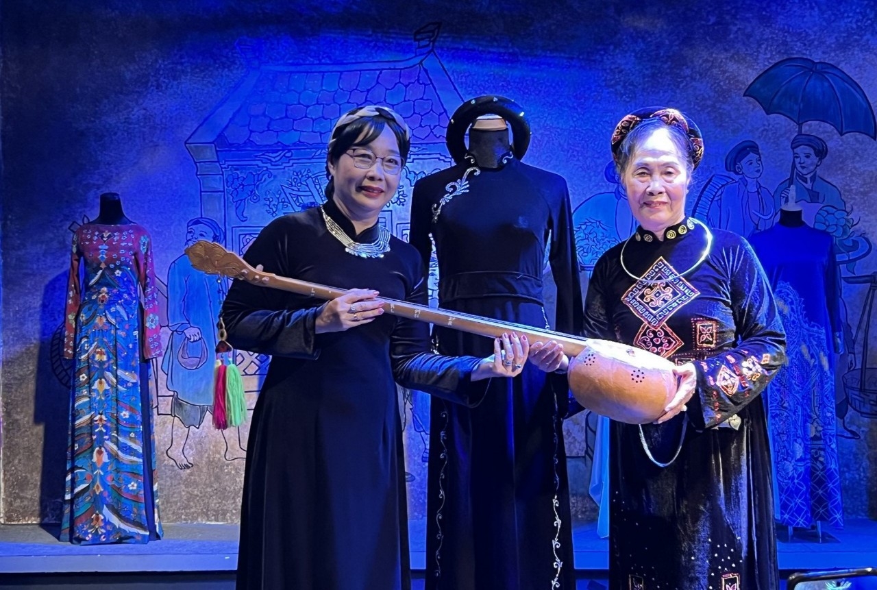 Nghệ nhân hát Then Nguyễn Thị Bích Liên (phải) trao tặng trang phục áo dài và đàn tính cho Bảo tàng Áo dài