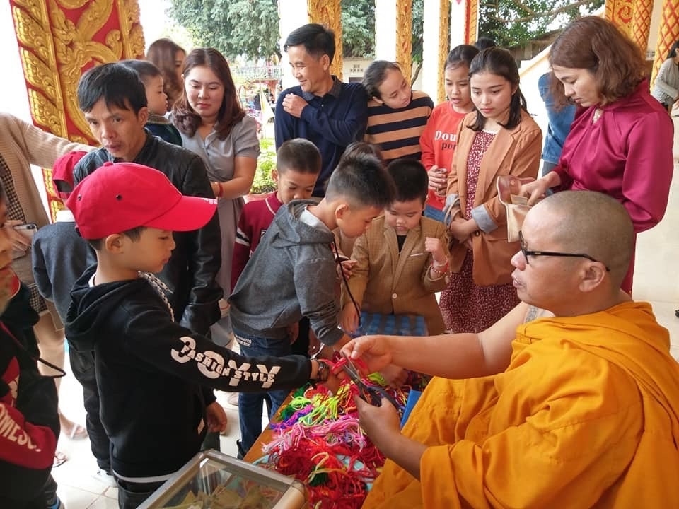 Du khách buộc chỉ tau cầu may ở chùa Ka Rôn, Lào