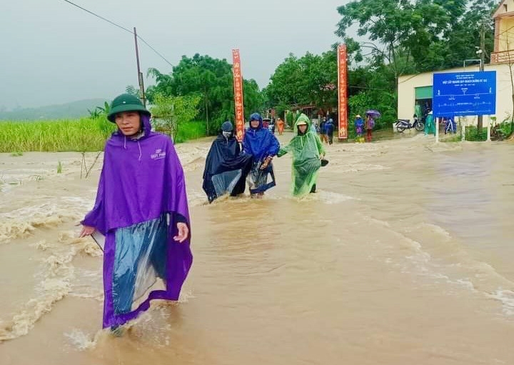 Nước lũ tràn qua đường khiến người dân đi lại gặp rất nhiều khó khăn và nguy hiểm