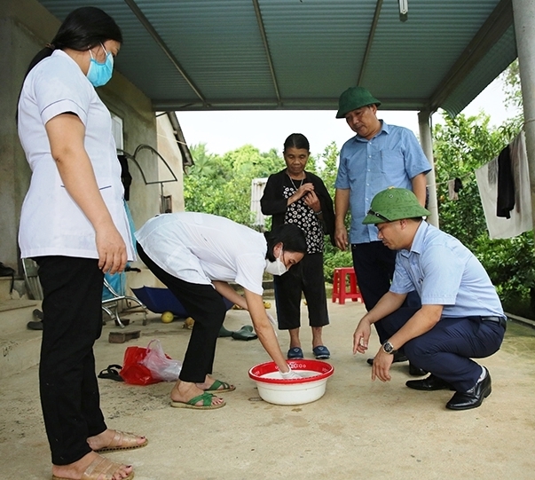 Cán bộ CDC Hà Tĩnh cùng với Trung tâm Y tế huyện Hương Khê hướng dẫn người dân pha Cloramin B để xử lý môi trường