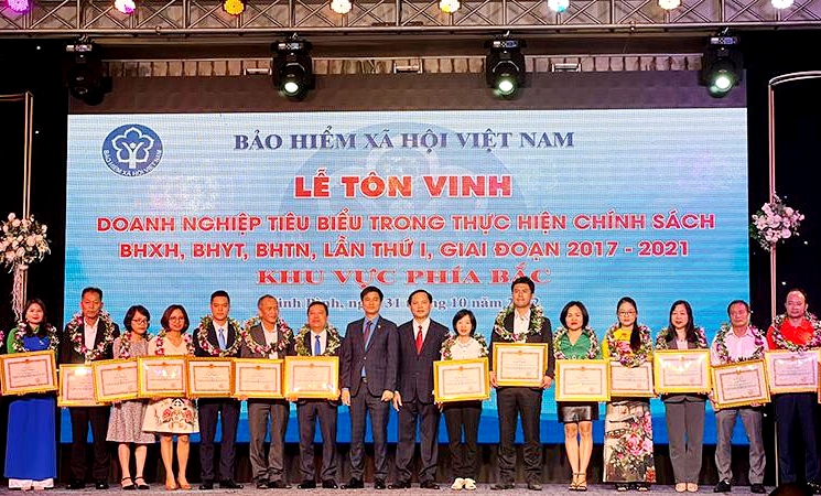 Lãnh đạo BHXH Việt Nam và VCCI trao Bằng khen và vòng nguyệt quế cho doanh nghiệp tiêu biểu.