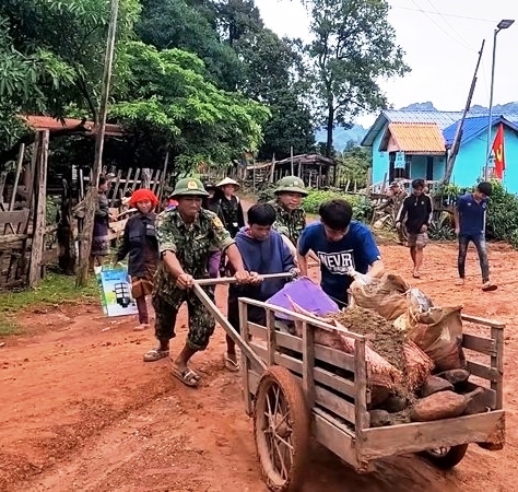 Nhân dân bản Na Chắt cùng BĐBP Việt Nam vận chuyển đất đá làm móng dựng chân cột điện - ảnh CTV