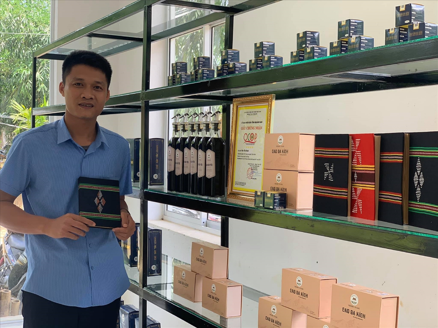 Ông Nguyễn Bá Hiển - Giám đốc HTX nông lâm nghiệp Thiên Bình với các sản phẩm OCOP từ HTX được sản xuất tại xã Lăng (huyện Tây Giang).