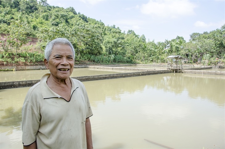 Già làng Hồ Thanh Bình bên khu nuôi cá đã trở thành hình mẫu cho bà con người Lào sang tham quan, học tập