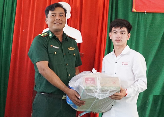 Trung tá Danh Kim Huol - Chính trị viên Đồn Biên phòng Cửa khẩu Giang Thành trao quà đến em Minh Sok Vinh là học sinh Campuchia được nhận học bổng Chương trình “Nâng bước em đến trường” của Bộ Tư lệnh Biên phòng
