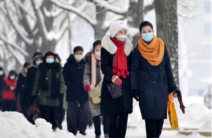 Người dân đeo khẩu trang đi trên một tuyến đường phủ đầy tuyết trắng tại thủ đô Bình Nhưỡng (Triều Tiên), ngày 21/12/2022. (Ảnh: Kyodo) 
