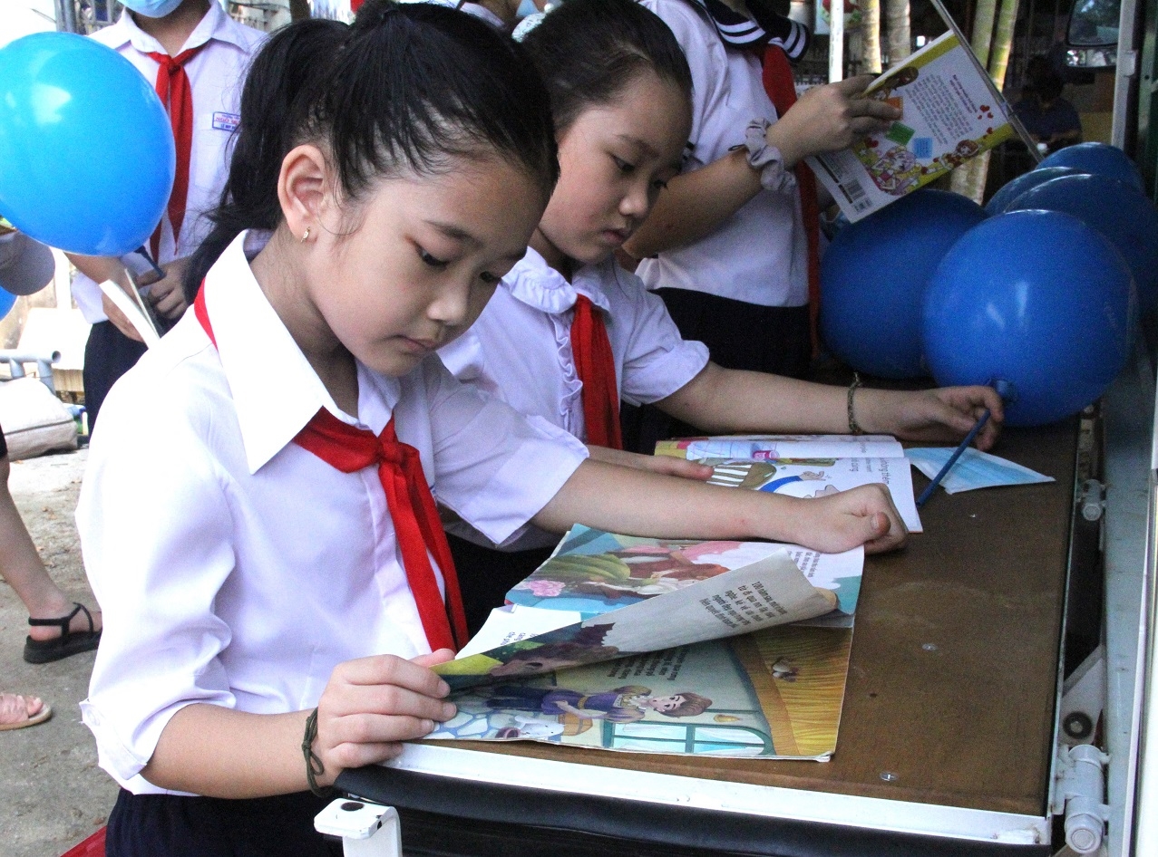 Các em học sinh đọc sách tại xe thư viện lưu động