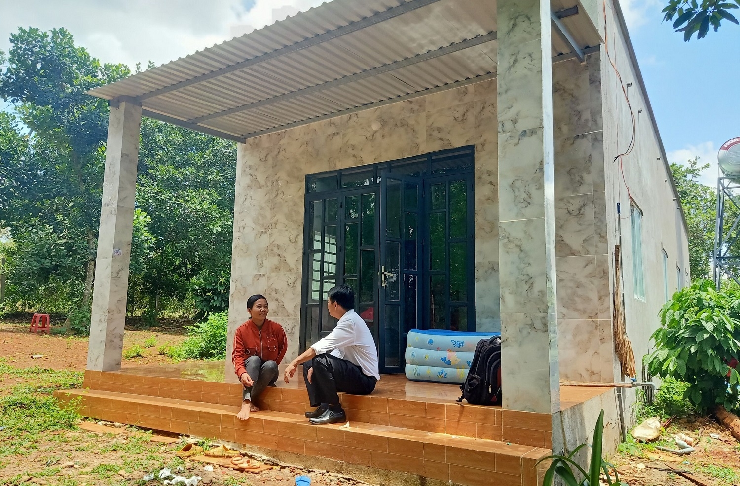 Chị Dương Thị Hoa (dân tộc Chơ Ro) ngồi trò chuyện với phóng viên trước ngôi nhà vừa xây mới theo Chương trình MTQG 1719