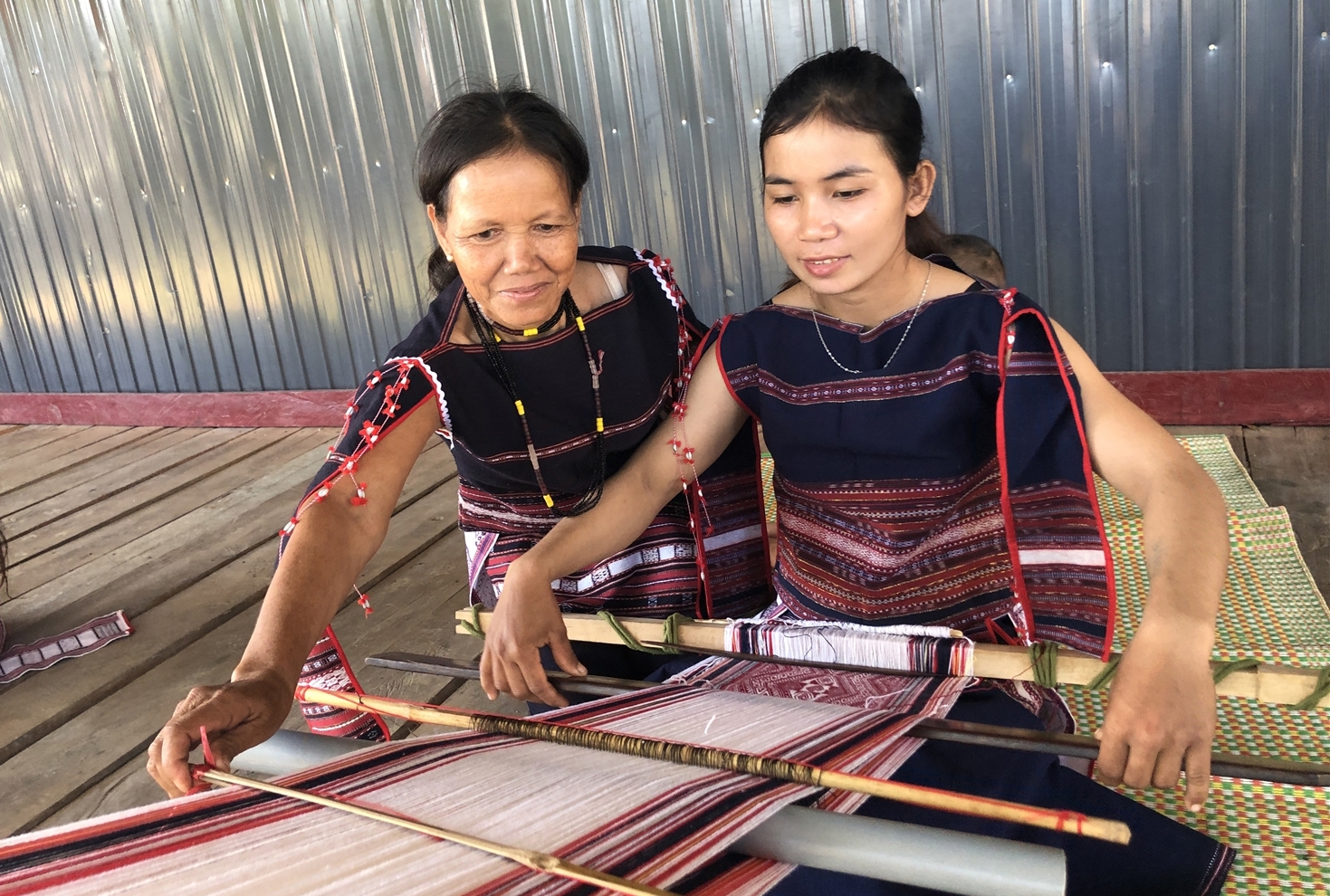 Nghệ nhân ưu tú Đinh Thị Dring huyện Kông Chro, Gia Lai (bên trái) đang truyền nghề dệt thổ cẩm cho lớp trẻ trong làng