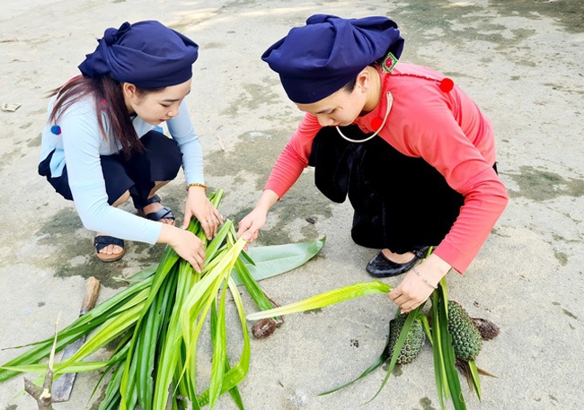 Phụ nữ lấy lá dứa rừng để tết đế yến - một dụng cụ trong trò chơi dân gian "đánh yến" của đồng bào Tày Nghĩa Đô trong ngày hội Xuân. (Ảnh: VGP/Lê Thanh Cường) 