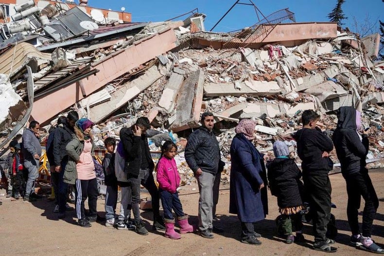 Người dân Thổ Nhĩ Kỳ xếp hàng bên đống đổ nát của trận động đất để nhận thực phẩm miễn phí. (Ảnh: Reuters)