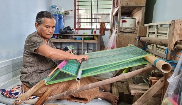 Nghệ nhân lớn tuổi người Chăm dệt vải thổ cẩm truyền thống. Ảnh: Nguyễn Thành – TTXVN