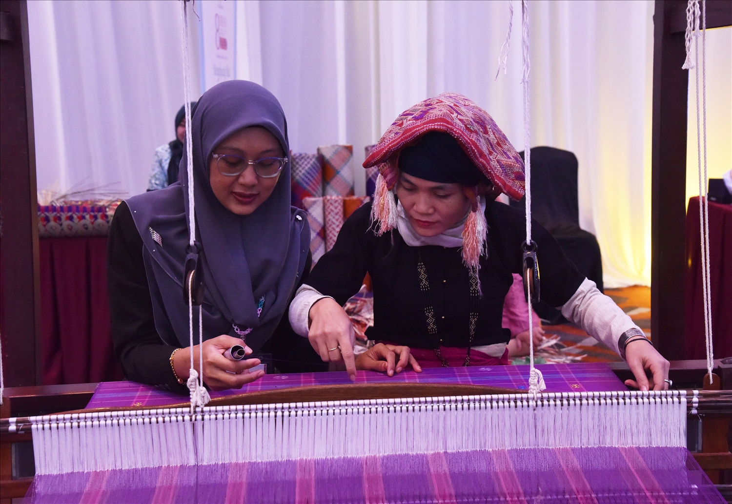 Sầm thị Tình đang trao đổi kỹ thuật dệt vải với nghệ nhân dệt Malaysia
