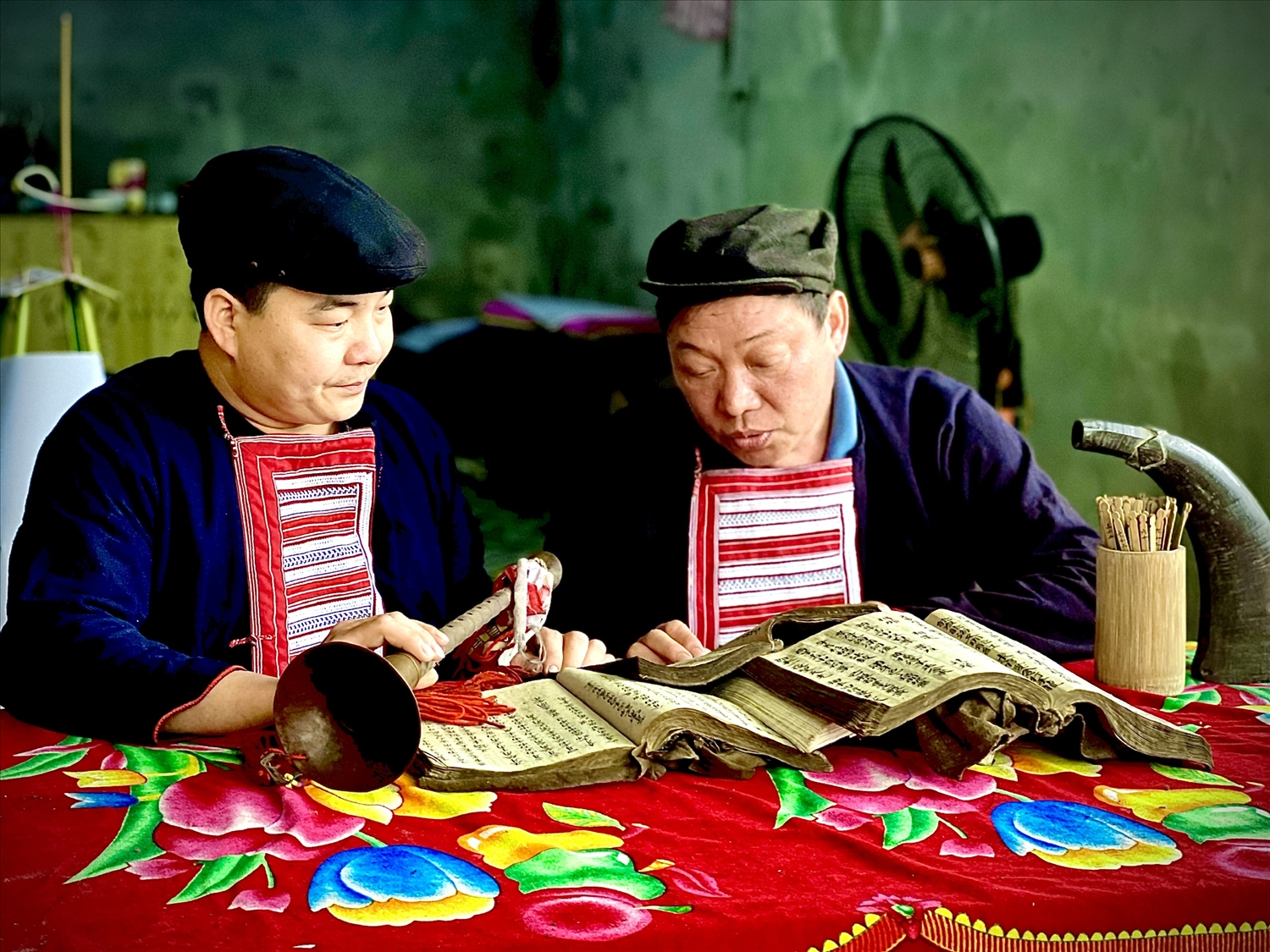 Nghệ nhân Phàn Văn Phú cùng con rể nghiên cứu sách cổ sử dụng nhạc cụ người Dao.