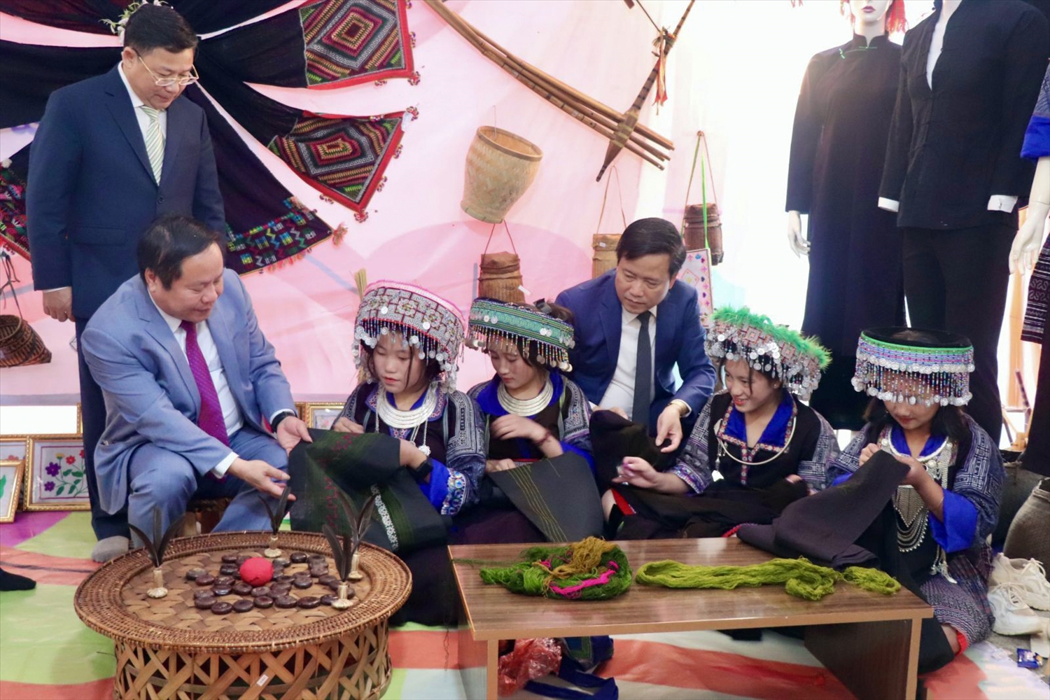 Các đại biểu tham quan, động viên các em học sinh dân tộc Mông tại không gian trưng bày các sản phẩm truyền thống 