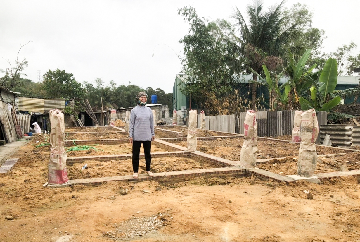 Chị Nguyễn Thị Huệ đứng trước móng nhà dang dở của gia đình