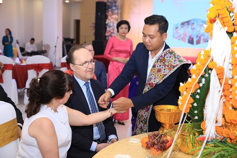 Cán bộ Đại sứ quán Lào buộc chỉ cổ tay chúc năm mới may mắn cho các khách mời quốc tế tham gia chương trình giao lưu