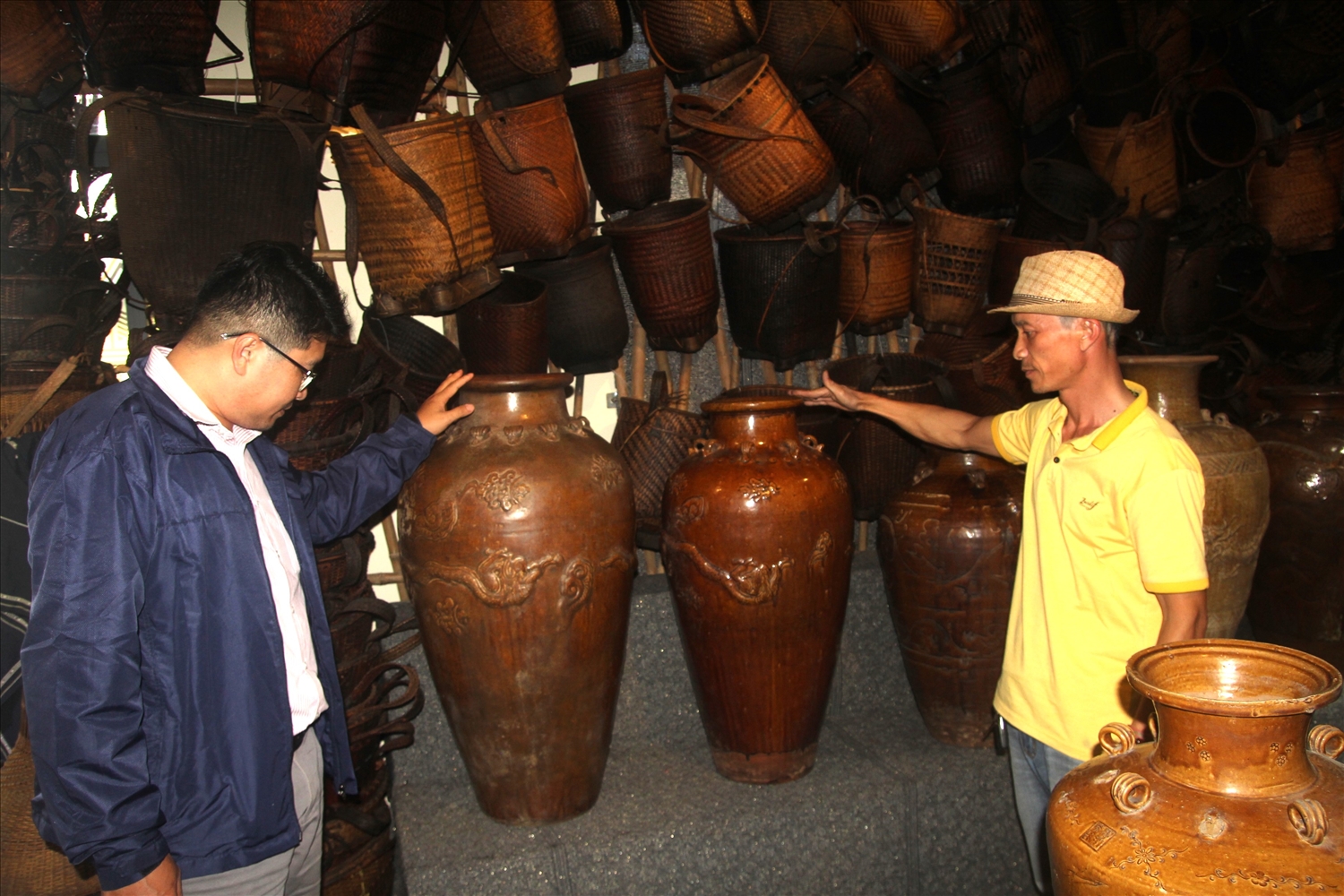 Anh Nguyễn Quốc Dũng (bên phải) giới thiệu những chiếc chum, ché cổ 