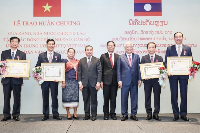 Chủ tịch Ủy ban Trung ương Mặt trận Lào xây dựng đất nước Sinlavong Khoutphaythoune và Chủ tịch Ủy ban Trung ương MTTQ Việt Nam Đỗ Văn Chiến chụp ảnh lưu niệm với các cá nhân được nhận Huân chương Ít-xa-la hạng II, III