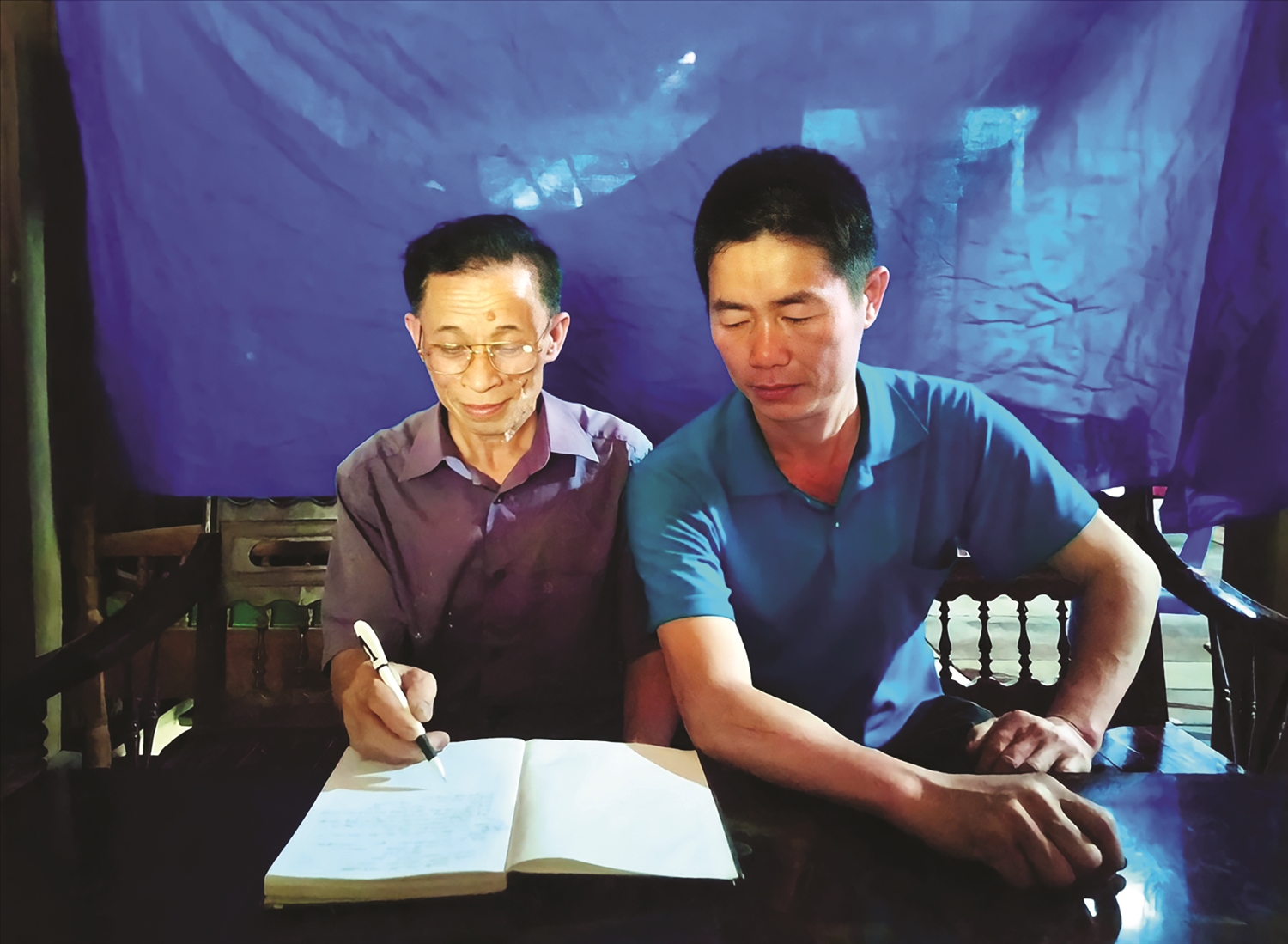 Ông Triệu Văn Lan (bên trái) trao đổi, chia sẻ thông tin với người dân.