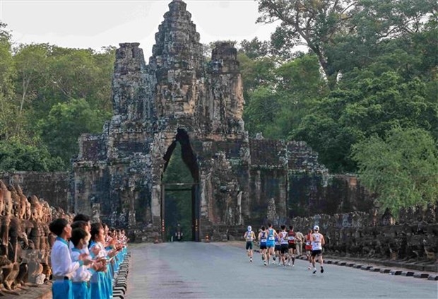 Các em học sinh chào đón, cỗ vũ các vận động viên Marathon trên các cung đường trong quần thể di tích Angkor Wat nổi tiếng ở cố đô Siem Reap của Vương quốc Campuchia. (Ảnh: AKP/TTXVN)