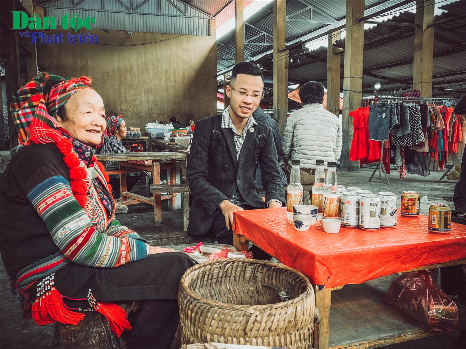 Phóng viên Báo Dân tộc và Phát triển cùng bà cụ Dân tộc Dao của xã trao đổi bên quán nước hông chợ