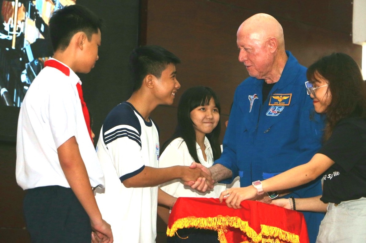Cựu phi hành gia Michael Baker trao quà lưu niệm cho các em học sinh tham gia gia lưu tại buổi lễ khai mạc 
