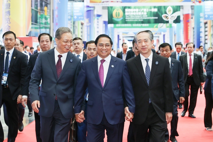 Thủ tướng Phạm Minh Chính, Bí thư tỉnh Quảng Tây (trái), Đại sứ Trung Quốc tại Việt Nam (phải) tham quan các gian hàng tại Hội chợ - Ảnh: VGP/Nhật Bắc