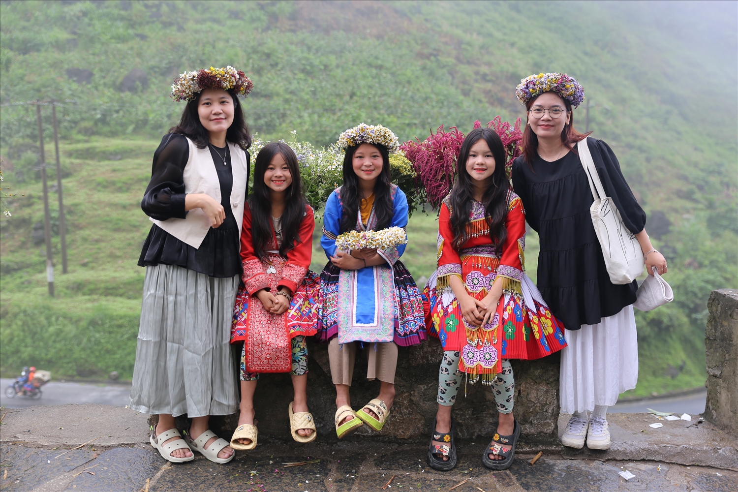 Khách du lịch chụp ảnh cùng các bé gái người Mông với những quẩy tấu hoa rực rỡ sắc màu tại Dốc Thẩm Mã