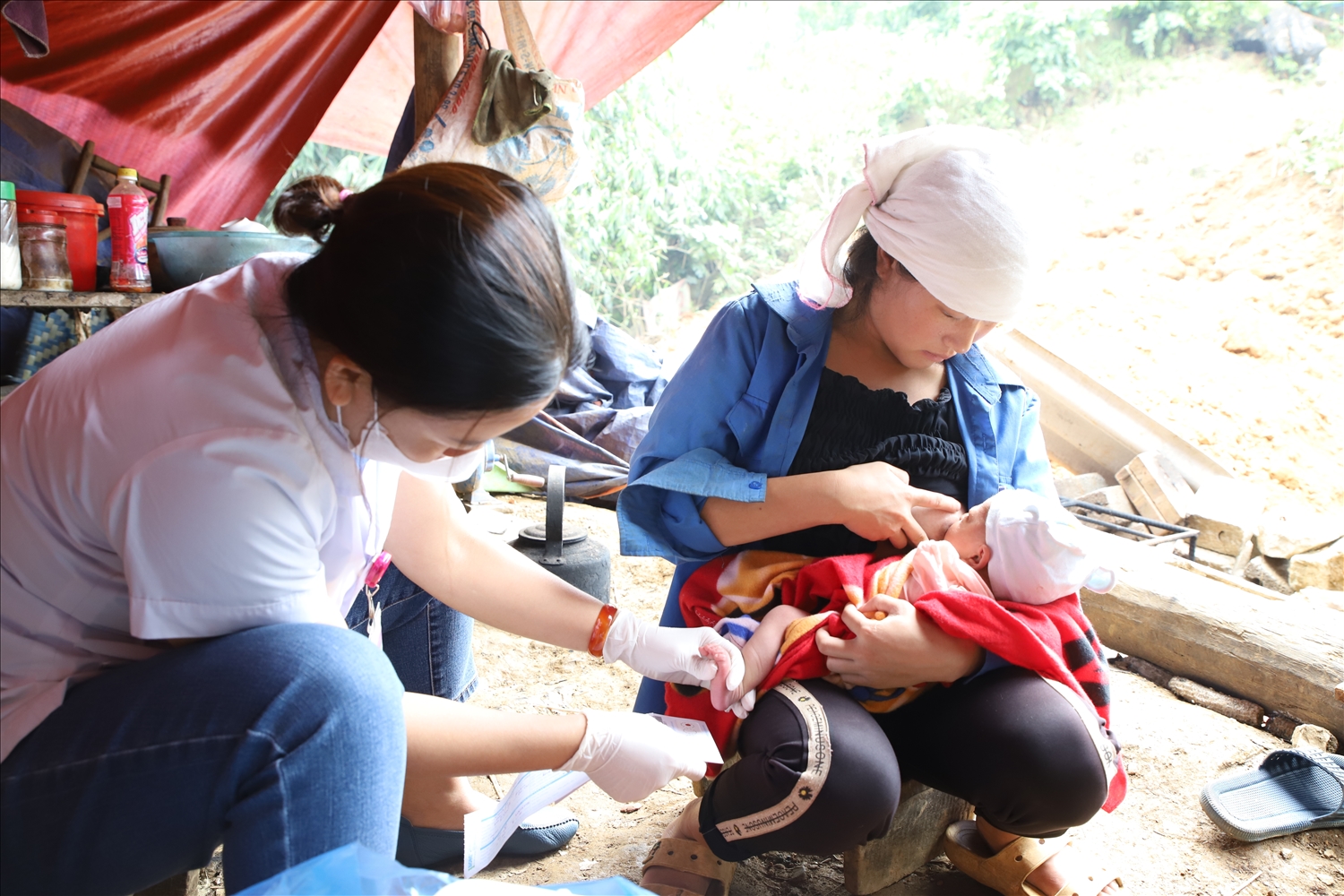 Chị Nguyễn Thị Vân Anh, cán bộ y tế đang lấy máu gót chân cho trẻ sơ sinh tại nhà