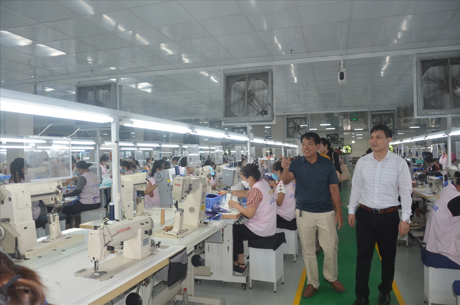 Ông Cao Hùng Dũng (bên phải) Chủ tịch Liên minh HTX tỉnh Tuyên Quang thăm dây chuyền sản xuất giầy xuất khẩu HTX Quang Minh (huyện Yên Sơn).