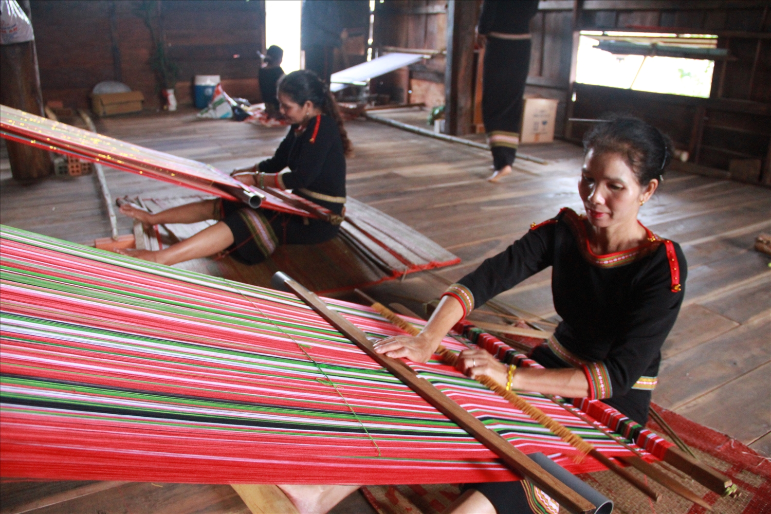 Các thành viên Tổ hợp tác dệt thổ cẩm Hra Ea Hning dệt tại nhà sinh hoạt cộng đồng buôn