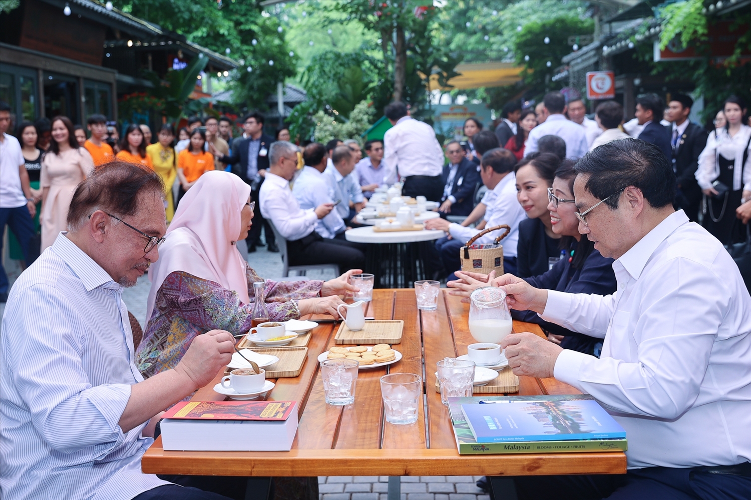 Thủ tướng Phạm Minh Chính và Thủ tướng Anwar Ibrahim cùng hai Phu nhân cùng xem sách, bên ly cà phê kết tinh từ đất, nước, nắng, gió Việt Nam, được chăm sóc bởi bàn tay của người dân vùng đất Cầu Đất, tỉnh Lâm Đồng - Ảnh: VGP/Nhật Bắc