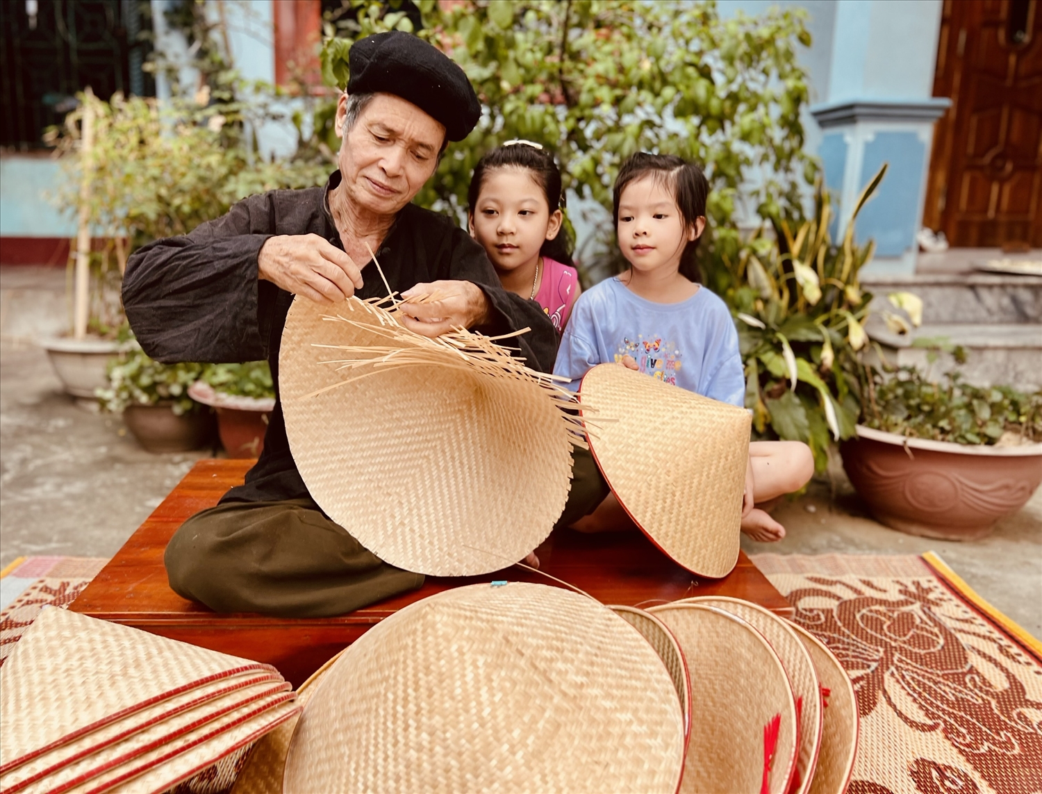 Ông Quan Văn Ơn hướng dẫn cách đan nón cho các cháu gái.